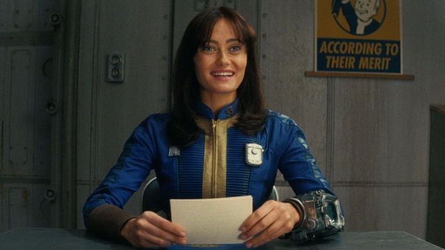 Lucy sitting a table in the vault in the Fallout television series.